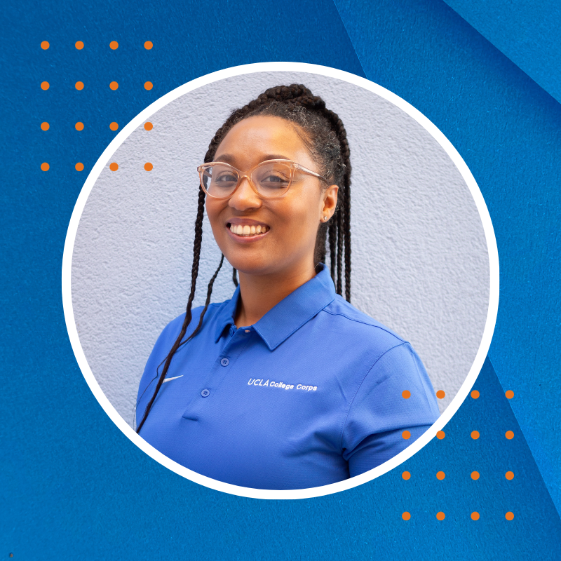 A smiling Black woman with long braids, in a blue shirt